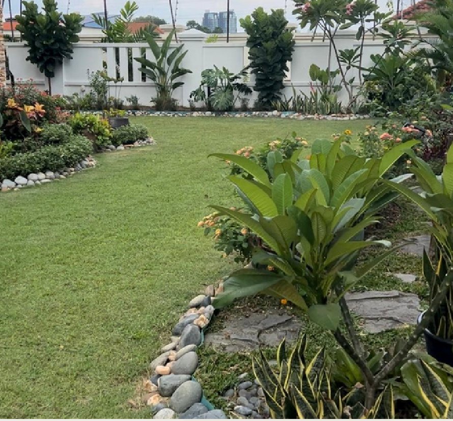 A lawn edged with river stones, with planted beds of shrubs and a stepping-stone path beside it