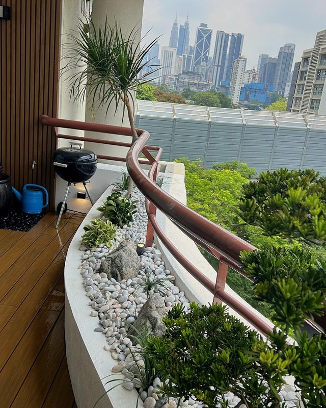 Balcony planter of pebbles, rocks and foliage curving towards the Kuala Lumpur skyline.